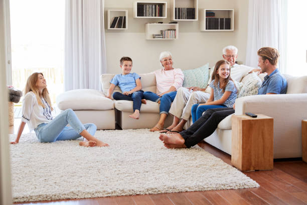 Multi Generation Family Relaxing On Deep Sectional Sofa At Home Together
