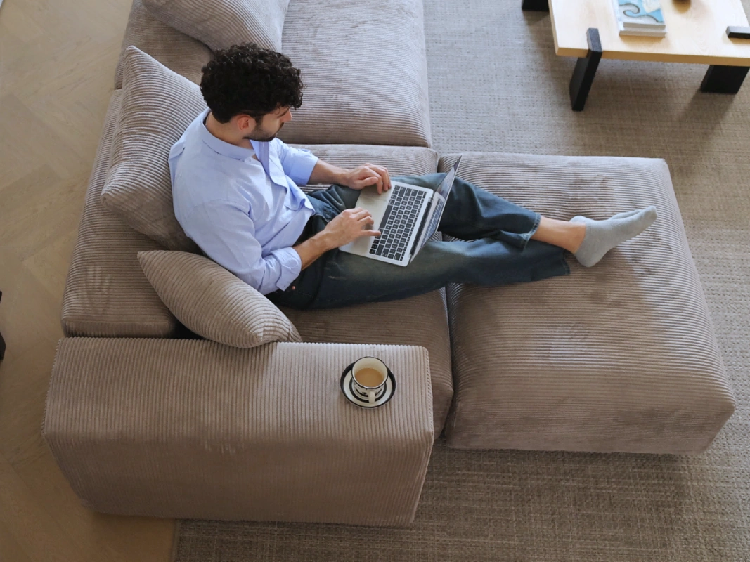 a man sits on a sectional sofa with chaise